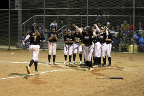 Dragon softball players round home plate as Madi Johnson arrives after a home run bomb